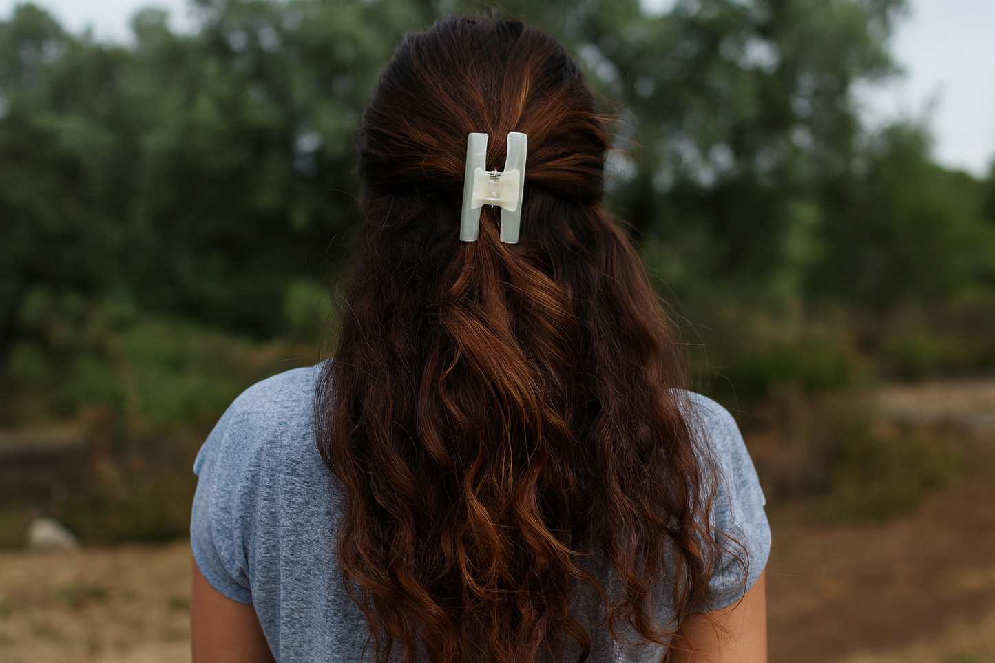 Hair clip on model with thick wavy hair - back view half-up style