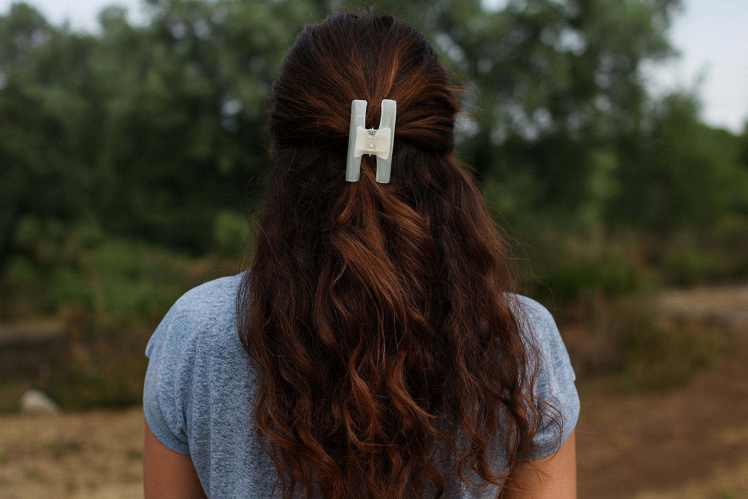 Hair clip on model with thick wavy hair - back view half-up style